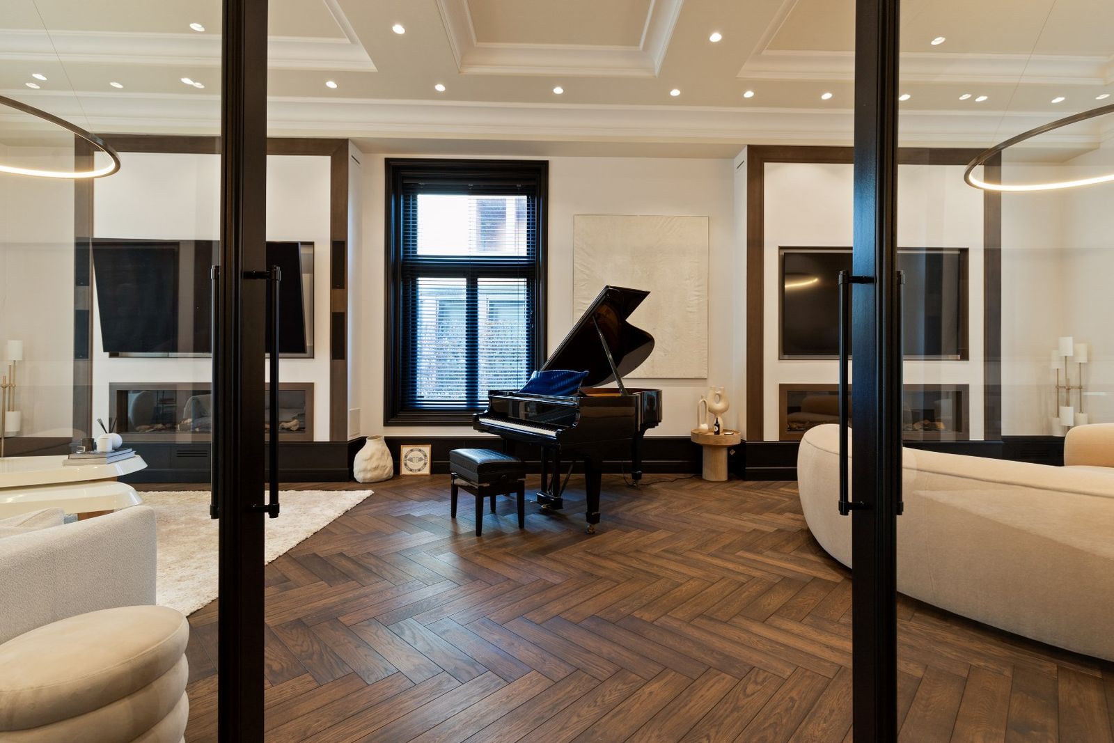 Stijlvolle woonkamer met een prachtige visgraadvloer, een zwarte vleugel in het midden, omgeven door moderne meubels en een strakke afwerking.