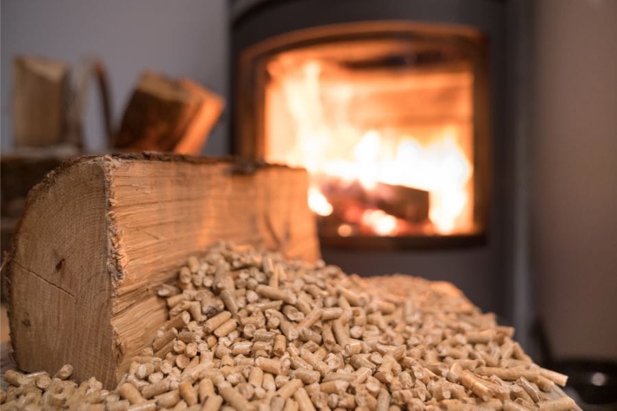 Warm en duurzaam houtkachel met brandende vlammen, houtblokken en houtpellets op de voorgrond