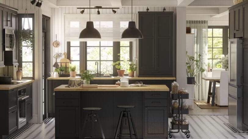 Donkere IKEA-keuken met houten blad, trolley en veel groen bij het raam