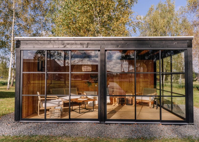 Glazen tuinkamer in de tuin met eettafel en zithoek